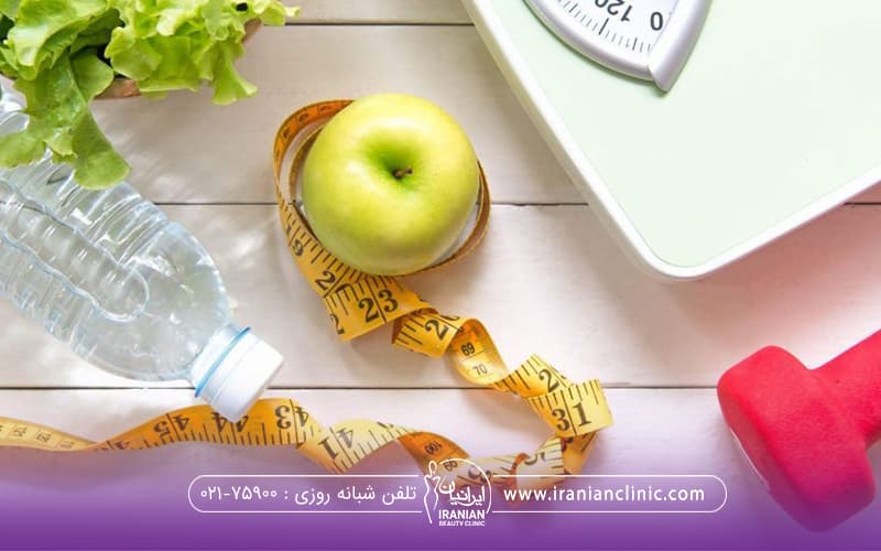 روی زمین یک سیب و یک متر دور سیب شیشه آب و ترازو و دز گوشه دمبل قرار دارد و تمرین و تغذیه لاغری را نمایش می دهد.